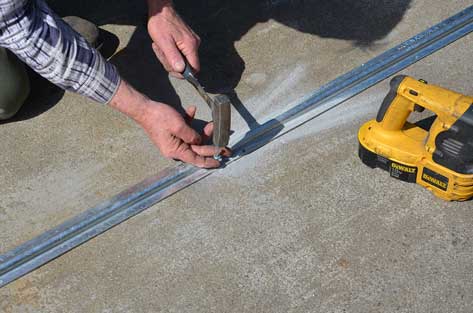 inserting nails to hold down sliding gate track